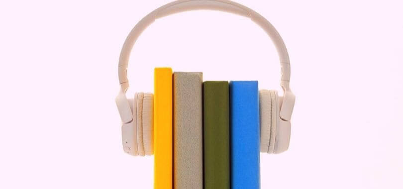 Four books held together with a pair of headphones.