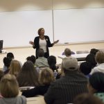 A professor talking to students and parents in a classroom.