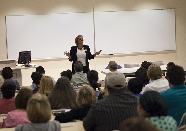 A professor talking to students and parents in a classroom.