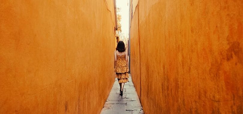 A person walking down a narrow alleyway.