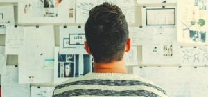 A student standing in front of papers stuck to a wall.