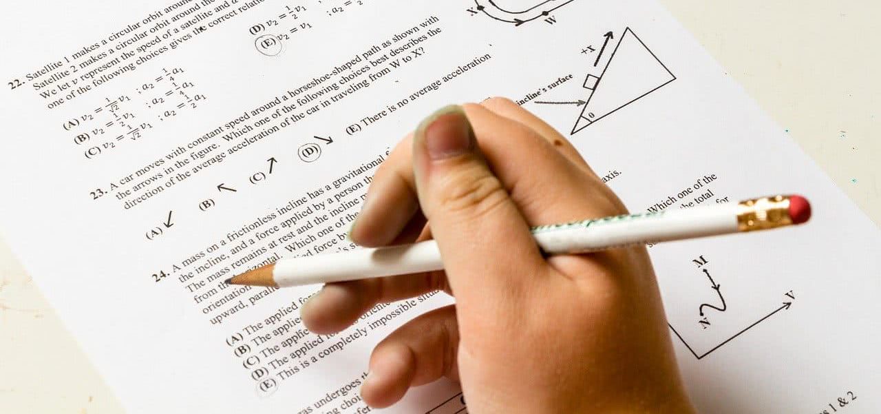 A student holding a pencil over a test sheet.