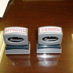 Two grey stampers, one says Approved, the other says Denied.