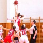 Students playing basketball with a referee standing at the side.