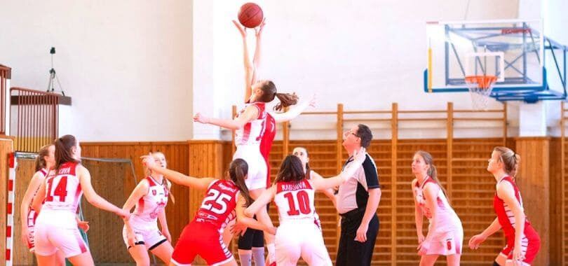 Students playing basketball with a referee standing at the side.