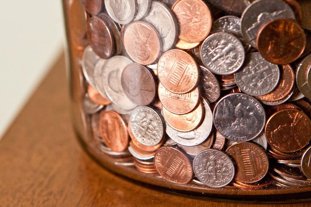 A jar of coins, mostly pennies and dimes.