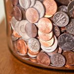 A jar of coins, mostly pennies and dimes.