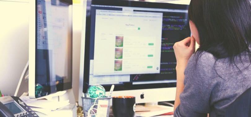 A person sitting in front of multiple computer monitors.