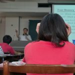 Students sitting in a classroom listening to a professor lecture.