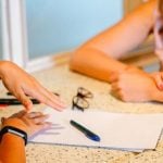 A student and an administrator conducting a college interview while sitting at a desk.