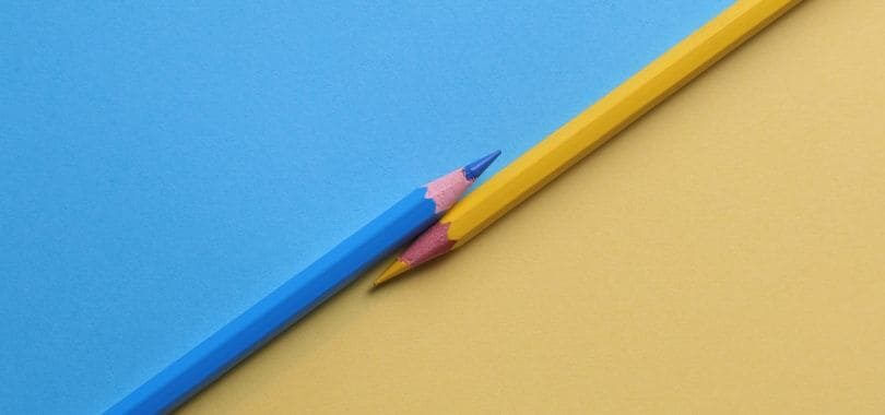 A blue and yellow pencil parallel to each other, with a blue and yellow background.