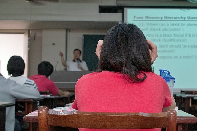 Students sitting in a classroom listening to a professor lecture.