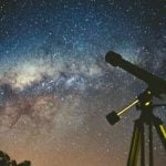 A starry night sky with a telescope in the corner.