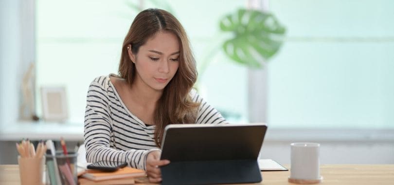 A student sitting at a table with a tablet.