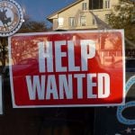 "Help Wanted" signage behind a glass wall.