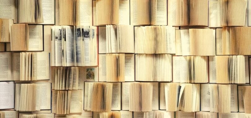Rows of books opened towards the camera, with one large textbook standing out.