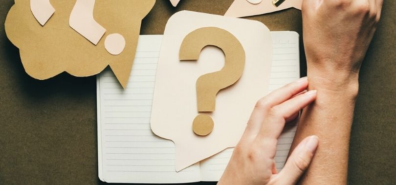 A question mark cut out laying on top of a journal.