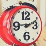 A red alarm clock with black numbers and white alarm bell.