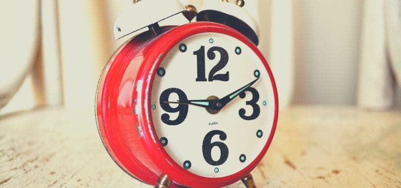 A red alarm clock with black numbers and white alarm bell.
