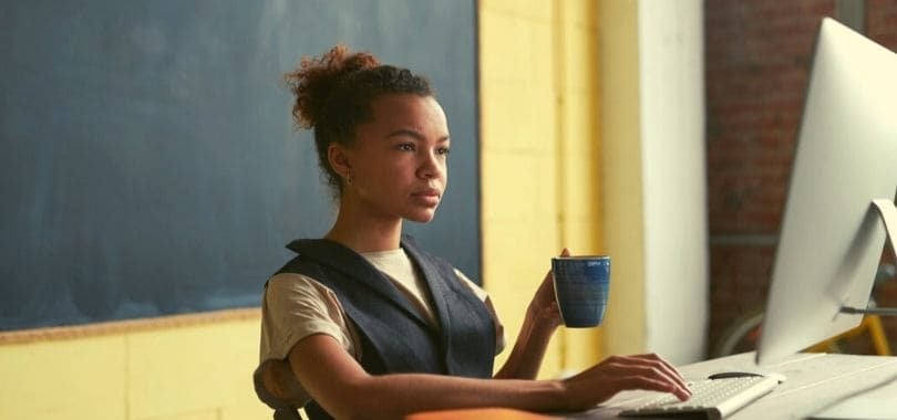 A teacher sitting at a desk in front of a computer.