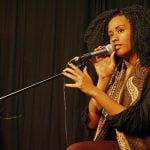 College student sitting on a stage speaking into a microphone.