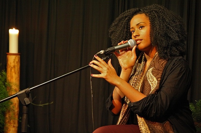 College student sitting on a stage speaking into a microphone.