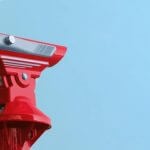 A pair of red binoculars outside against a blue sky.