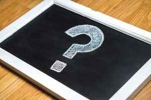A question mark written in a small chalkboard that is lying on the floor.