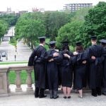 Back view of graduate students hugging each other.