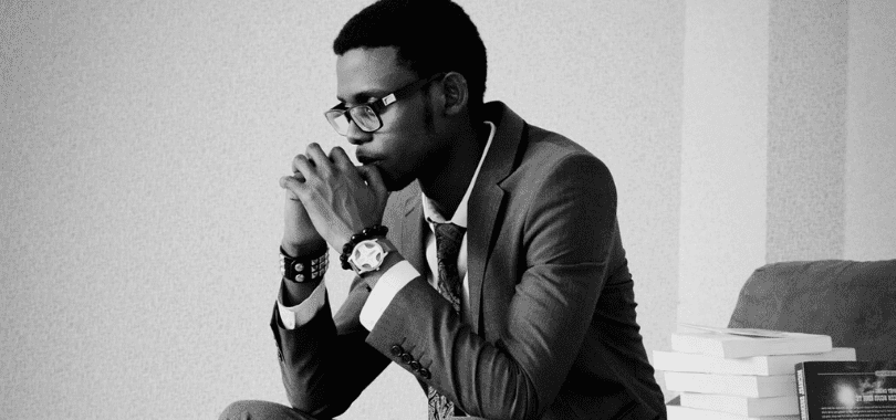 A black and white picture of a student thinking with their chin resting on their hands.