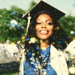 A graduating student with their hands out throwing glitter.