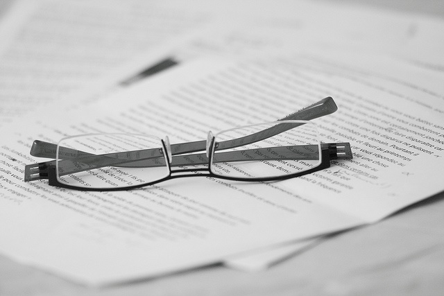 Eyeglass is on the top of white papers.