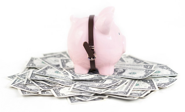 Piggy bank standing over paper dollar bills.