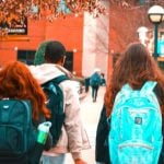 A group of students wearing backpacks walking together.