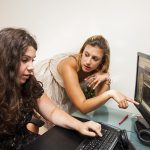 Two girls discussing infront of the computer.