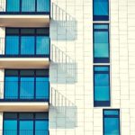 A white brick apartment building against a blue sky.