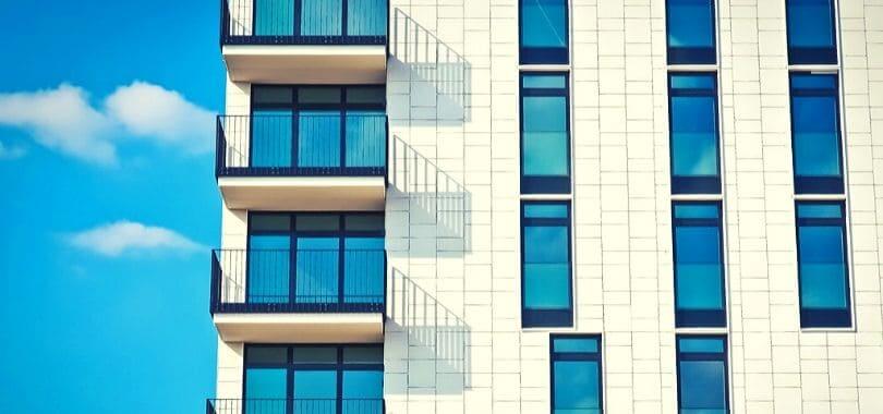 A white brick apartment building against a blue sky.