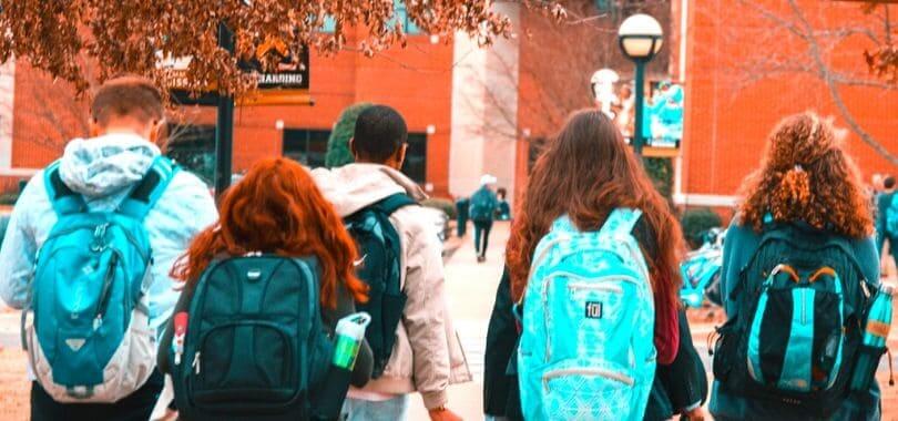 A group of students wearing backpacks walking together.