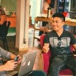 Two students talking to each other at a cafe.