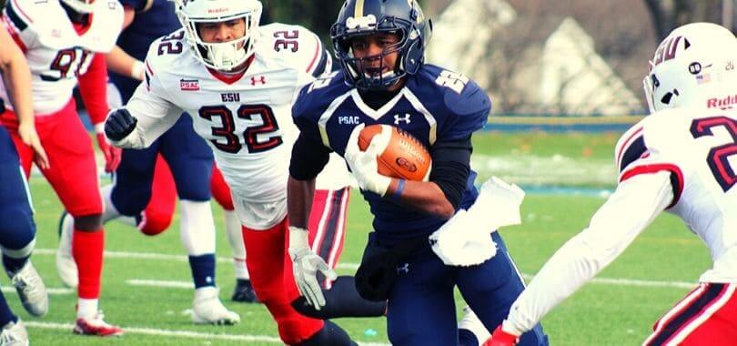 A football player holding a football while being surrounded by other players.