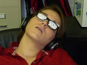 A guy sleeping while wearing eye glasses with doodles on it.
