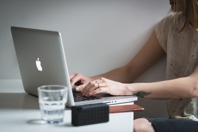 Student sitting at her dorm desk typing an essay on her Macbook.