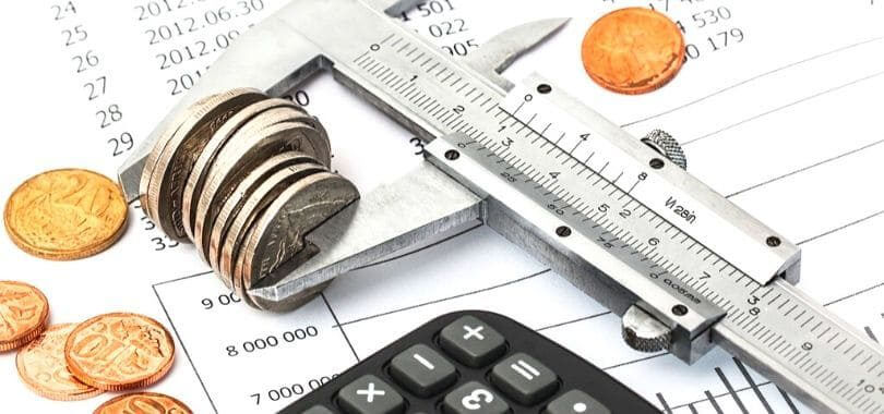 A ruler pinching together a stack of coins.