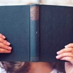 A person holding a book up to their face.