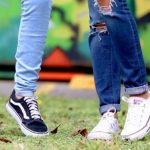 Two students standing together on grass.