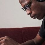 A student wearing headphones and reading.