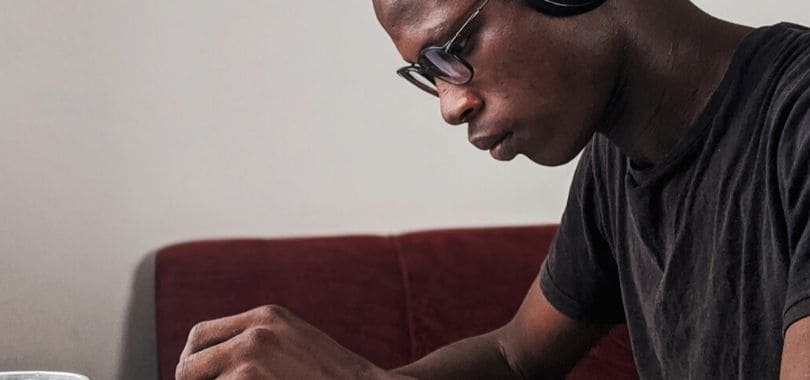 A student wearing headphones and reading.