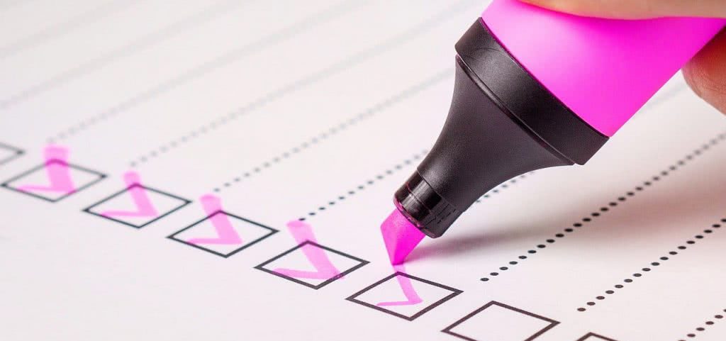 A pink highlighter and check marks on a piece of paper.