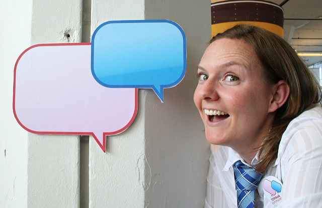 A woman is smiling with two speech bubble beside in front of her.