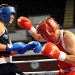 Two boxers fighting on the ring - one is punching.